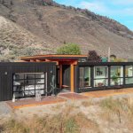 Exterior view of modern two-bedroom shipping container home surrounded by forest