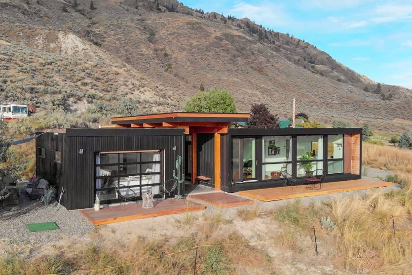 Exterior view of modern two-bedroom shipping container home surrounded by forest