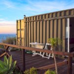 Off-grid tiny house made from a 20-foot shipping container beside a tranquil lake