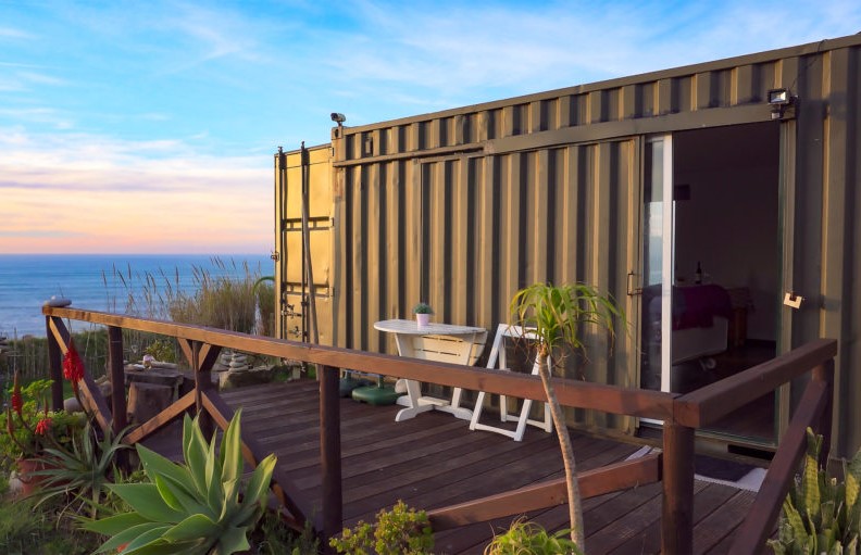 Off-grid tiny house made from a 20-foot shipping container beside a tranquil lake