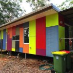A wide shot of the 40-foot shipping container tiny house showing its sleek black exterior and large wooden deck on Russell Island
