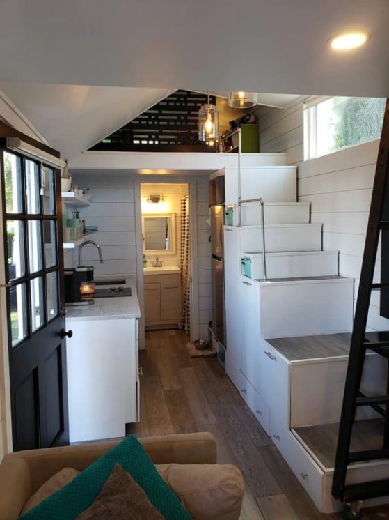 Cozy living area with electric fireplace, folding dining table, and ladder to the loft.